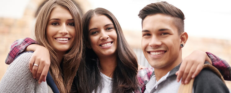 two teenage girls and one teenage boy, smiling