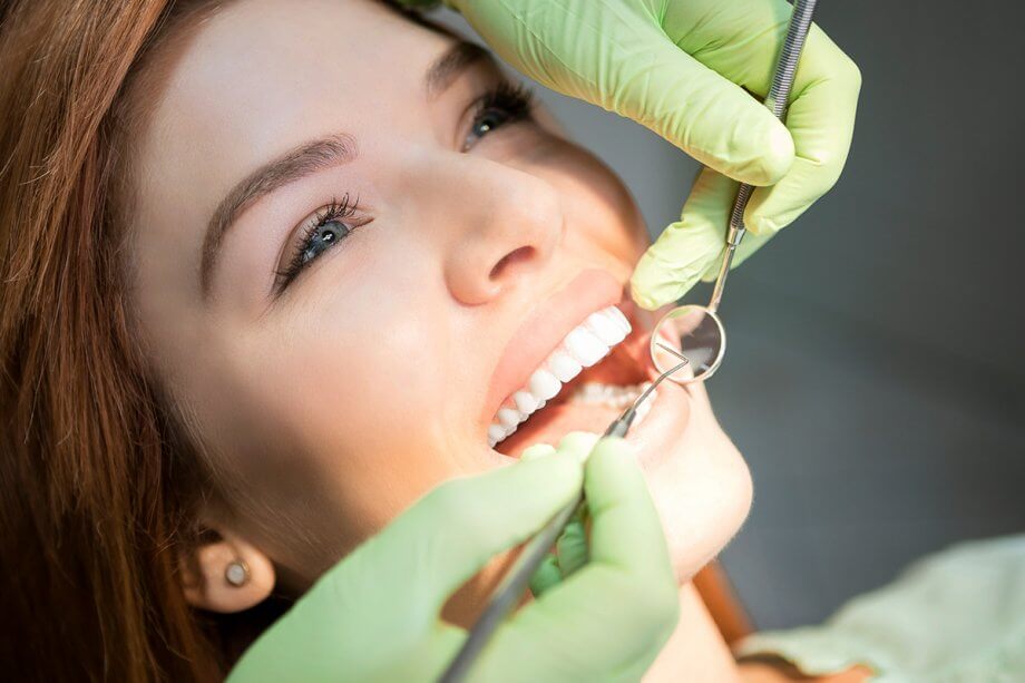 female patient having teeth examined with dental tools