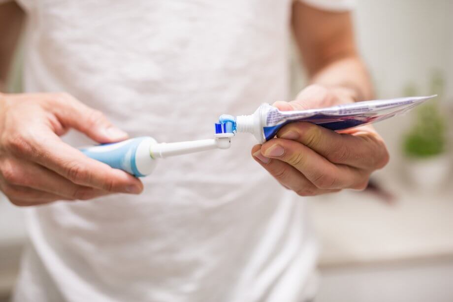 Man Putting Toothpaste on Electric Toothbrush