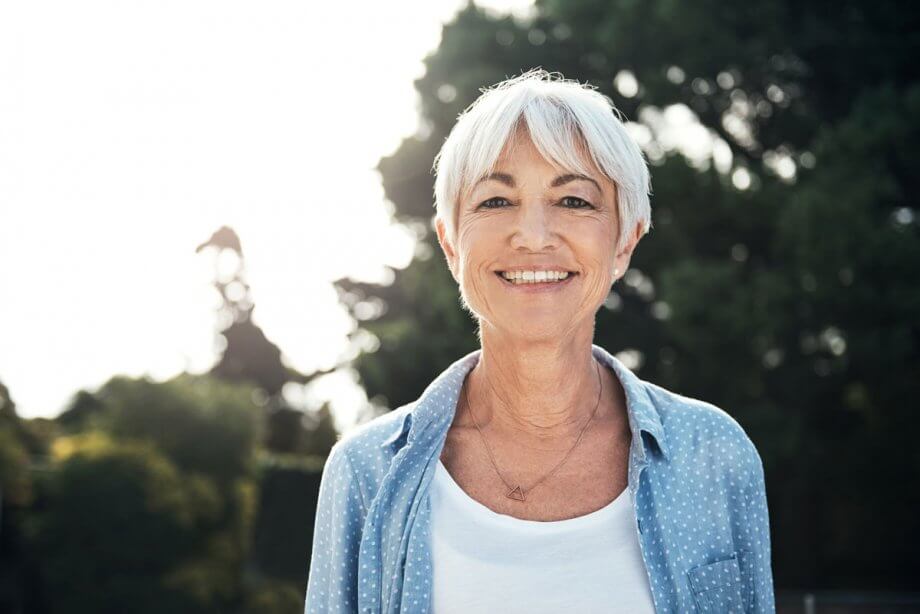 smiling older woman standing outside on a sunny day