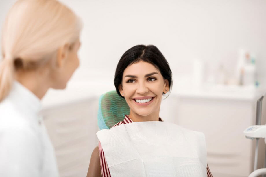 female patient in dental exam chair smiling at dentist